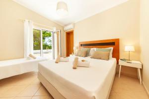a white bedroom with a large bed and a window at Villa Solara - com piscina aquecível e BBQ em Carvoeiro in Carvoeiro +42 photos