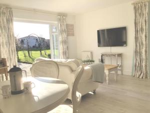 a living room with white furniture and a flat screen tv at The Meadows, OXTED in Tandridge