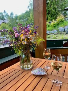 a table with a vase of flowers and two glasses of wine at Alpenliebe in Bad Kleinkirchheim
