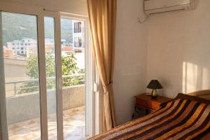 a bedroom with a bed and a balcony with a window at Villa del Mare in Dobra Voda