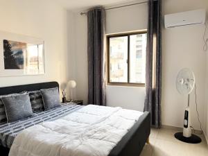 a bedroom with a bed and a window and a fan at Résidence Uria in Libreville