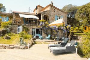 a stone house with a patio and an umbrella at Idyllic French farmhouse in Les Assions