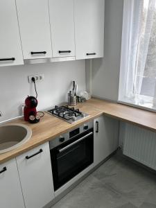a kitchen with white cabinets and a stove and a sink at 7 min walking to airport in Otopeni +15 photos