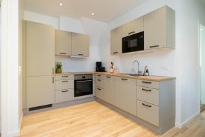 a kitchen with white cabinets and a wooden floor at Lønstrup Apartments, Klitrose in Lønstrup