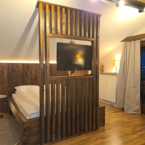 a room with a tv and a wooden wall at BergLiebe in Unterammergau