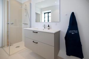 a white bathroom with a sink and a mirror at Lønstrup Apartments, Klitrose in Lønstrup