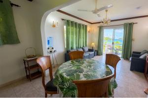 a dining room with a table and chairs and a couch at Villa Bel Age Seychelles in Anse Royale