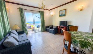 a living room with a couch and a television at Villa Bel Age Seychelles in Anse Royale