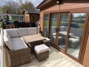 a screened porch with a couch and wicker chairs at S&K Lodge Billing Aquadrome Holiday Park, Great billing ,Northampton , NN3 9DA in Northampton
