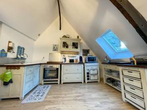 an attic kitchen with white cabinets and a window at Poutres et charme in Paimpol +12 photos