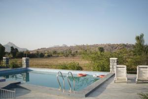a swimming pool with two lawn chairs next to it at Soma Jawai in Bijāpur
