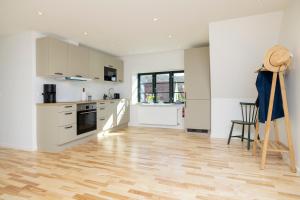 a kitchen with white cabinets and a wooden floor at Lønstrup Apartments, Havtorn in Lønstrup +8 photos