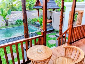 a balcony with a table and chairs and a swimming pool at Bene Pertiwi Villa in Ubud