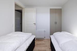 two beds in a room with white walls and wooden floors at Lønstrup Apartments, Havtorn in Lønstrup