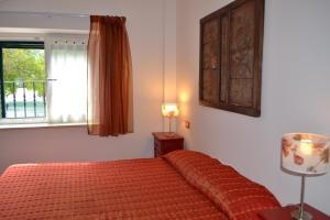 a bedroom with a bed with an orange bedspread and a window at La Maga del Lago in Scanno