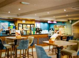 a restaurant with tables and chairs and a counter at 5 Minutes Walk From Beach , Fully Disabled,Pet Friendly Caravan With Hot Tub On Coastfields Holiday Village in Skegness