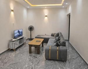 a living room with a couch and a table and a tv at Adesta Suites in Ilorin