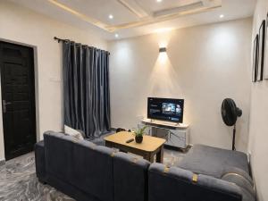 a living room with a blue couch and a television at Adesta Suites in Ilorin