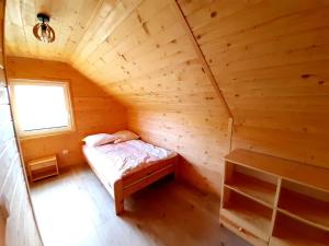 a small bed in a wooden room with a window at Domek w górach Lachowice in Lachowice