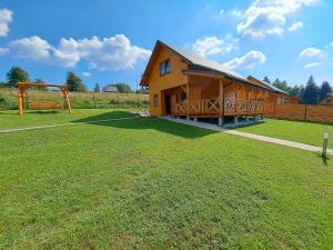 a wooden cabin with a large grass field at Domek w górach Lachowice in Lachowice