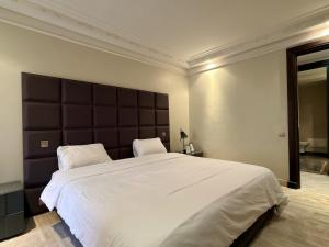 a bedroom with a large white bed with a large headboard at Residence jardin ocre in Marrakesh
