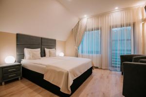a bedroom with a large bed and two windows at Mountain Paradise & Wellness in Izvoare +38 photos