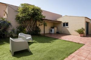 a yard with two white chairs in the grass at Mindelo Beach House in Vila Chã