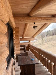 a porch of a log cabin with a wooden table at Cabanele 2 Mitici in Săliştea de Sus