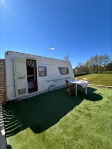 a white trailer with a table in the grass at Gite Esprit Etape in Saint-Barthélemy-de-Vals