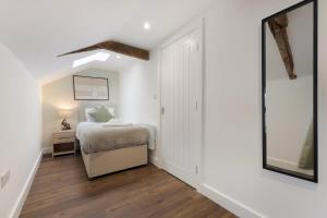 a white bedroom with a bed and a mirror at Flat4 1BR in Horsemarket in Barnard Castle
