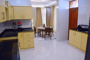 a kitchen with yellow cabinets and a table with chairs at DDS Homes Apartments in Dodoma