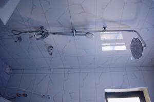 a bathroom with a shower with a white marble wall at DDS Homes Apartments in Dodoma +18 photos