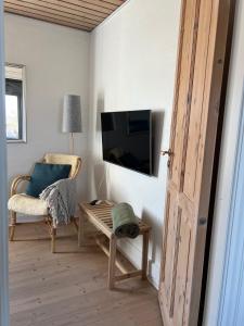 a living room with a tv and a chair and a table at Charming sunroom with panorama view in Randers