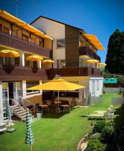a large building with yellow umbrellas in a yard at Kurhotel Wiedenmann in Bad Wörishofen