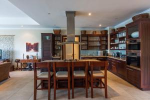 a kitchen with wooden cabinets and a table and chairs at PRIVATE SEA VIEW VILLA Eden Island in Eden Island