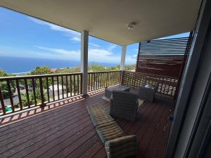 a deck with a couch and chairs on a balcony at Villa Papang in Saint-Paul