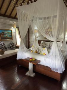 a bedroom with a bed with white mosquito nets at The Jingga Villas in Nusa Lembongan