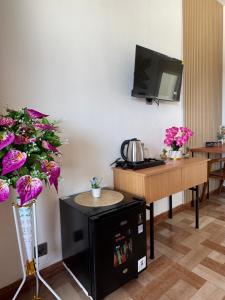 a room with a table and a tv and flowers at Holi Saren Guest House in Nusa Dua +14 photos