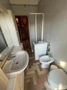 a white bathroom with a toilet and a sink at La dolce vela in Muggia +9 photos