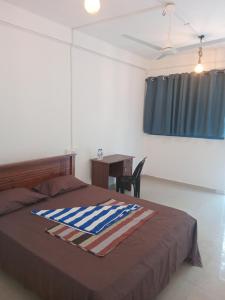 a bedroom with a bed with a desk and a window at Amaya Hotel and Restaurant in Batigama