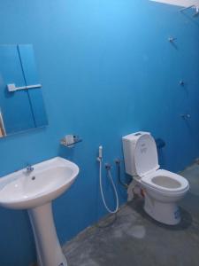 a blue bathroom with a toilet and a sink at Amaya Hotel and Restaurant in Batigama