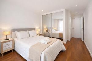 a bedroom with a large white bed and a mirror at City World Apartment in Maia