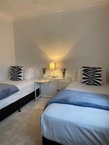 a bedroom with two beds and a table with a lamp at Family Haven Bradburry in Campbelltown South