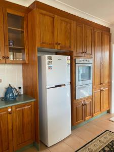 a kitchen with a white refrigerator and wooden cabinets at Family Haven Bradburry in Campbelltown South