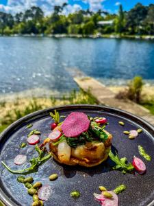 a plate of food on a table near a body of water at La Caravelle Logis in Biscarrosse