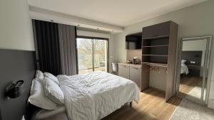 a bedroom with a white bed and a mirror at La Rose du Lac Hôtel Appart' in Coucouron