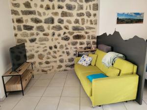 a living room with a yellow couch and a tv at Le Moulin des Puys in Orcines