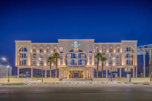 a large building with palm trees in front of it at Element by Marriott Al Qassim in Buraydah