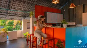 a woman sitting at a counter in a kitchen at Zostel Varkala in Varkala