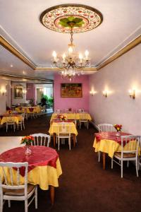 a dining room with tables and chairs and a chandelier at Hotel Saint Francois Xavier in Lourdes